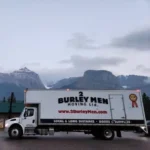 2 Burley Men Moving long-haul truck with the Rocky Mountains in the background.