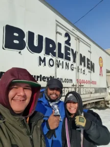 Smiling customers giving a thumbs up while standing beside a 2 Burley Men employee in front of a 2 Burley Men Moving truck.